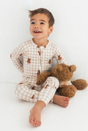Child wearing checkered pajamas with a teddy bear on a white background