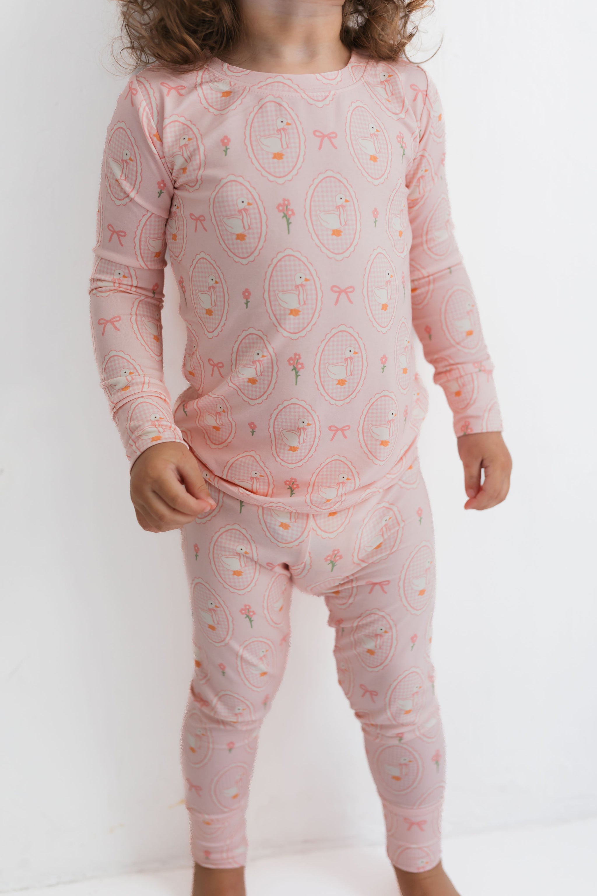 Child wearing pink pajamas with a pattern on a white background