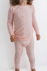 Child wearing pink pajamas with a pattern on a white background